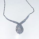A SILVER NECKLACE claw set to the centre with a trilogy floral design designed as an openwork