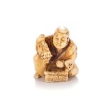 A JAPANESE IVORY NETSUKE OF A GRAPE SELLER, MEIJI PERIOD, 1868 - 1912 NOT SUITABLE FOR EXPORTThe