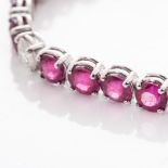 A DIAMOND AND RUBY TENNIS BRACELET claw set with 26 round brilliant cut enhanced Rubies weighing