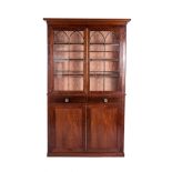 A VICTORIAN MAHOGANY BOOKCASE CABINET In two parts, the outswept cornice above a pair of astragal