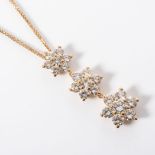 A DIAMOND PENDANT Designed as a trilogy of flower head pendants claw-set with 21 round brilliant