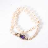 A STRAND OF CULTURED PEARLS each 7mm round pearl, knotted secured by a marquise shape 9ct rose
