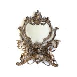 A SILVER PLATED DRESSING TABLE MIRROR The heart-shaped mirror centred by a scrolling crest flanked