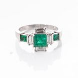 AN EMERALD AND DIAMOND RING Claw-set to the centre with a princess-cut emerald weighing
