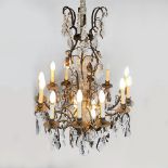 A METAL AND CRYSTAL TEN LIGHT CHANDELIER Each sconce on scrolling arms, suspended with crystal drops