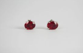 Pair of Ruby stud earrings, each set with an oval cut treated ruby, 4 claw set, stamped sterling