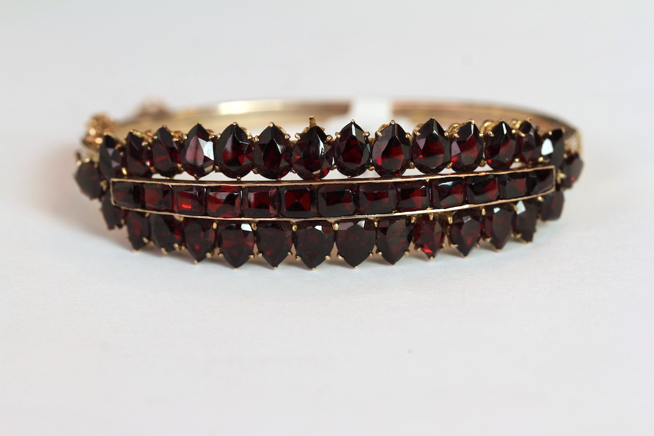 Early 20th Century Grnet set hinged bangle, mounted with a row of chanel set square cut Garnets, a