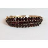 Early 20th Century Garnet set hinged bangle, mounted with a row of channel set square cut Garnets, a