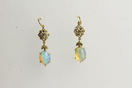 Pair of Opal Drop Earrings, each set with an oval cut opal, claw set, fish hook style.