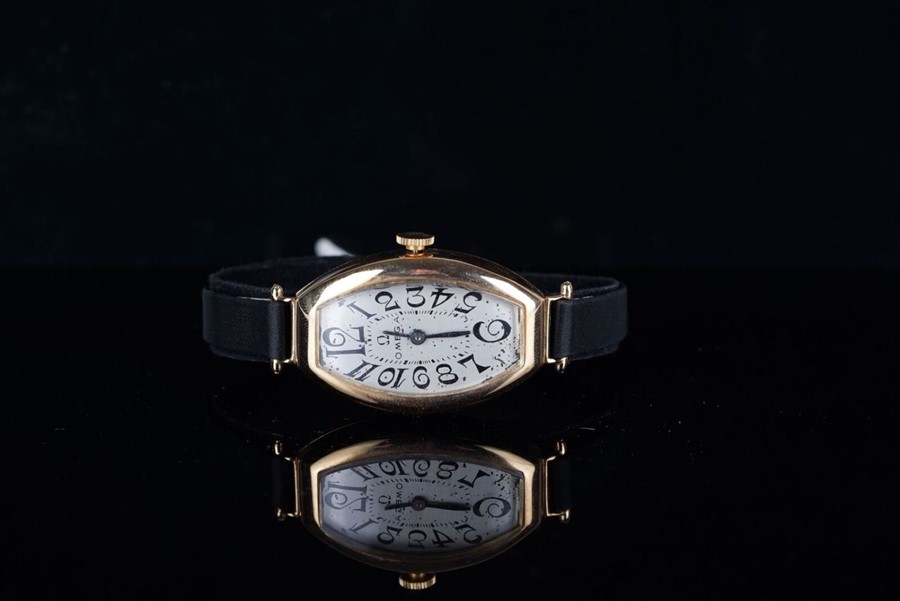 LADIES OMEGA 18CT GOLD WRISTWATCH CIRCA 1920s, tonneau shaped silver dial with black Arabic numerals