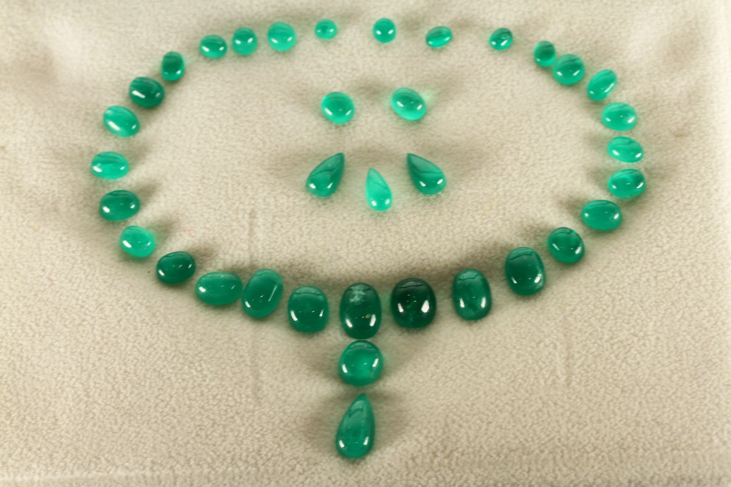 A Loose Set of Cabochon Emerald Stones, arranged as a graduating riviere with pear cabochon cut