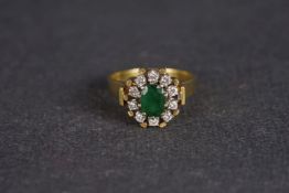 Emerald and diamond cluster ring, central oval cut emerald, a cluster of brilliant cut diamonds,