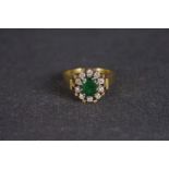 Emerald and diamond cluster ring, central oval cut emerald, a cluster of brilliant cut diamonds,