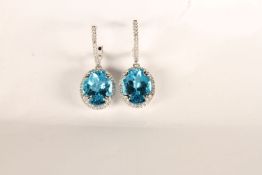 Pair of Blue Topaz and Diamond Drop Earrings, each set with an oval cut blue topaz, claw set,