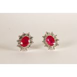 Pair of Ruby and Diamond Stud Earrings, each set with an oval cut ruby, total approximate ruby