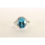 Blue Topaz and Diamond Ring, set with an oval cut blue topaz, claw set, surrounded by a halo of
