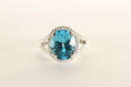 Blue Topaz and Diamond Ring, set with an oval cut blue topaz, claw set, surrounded by a halo of