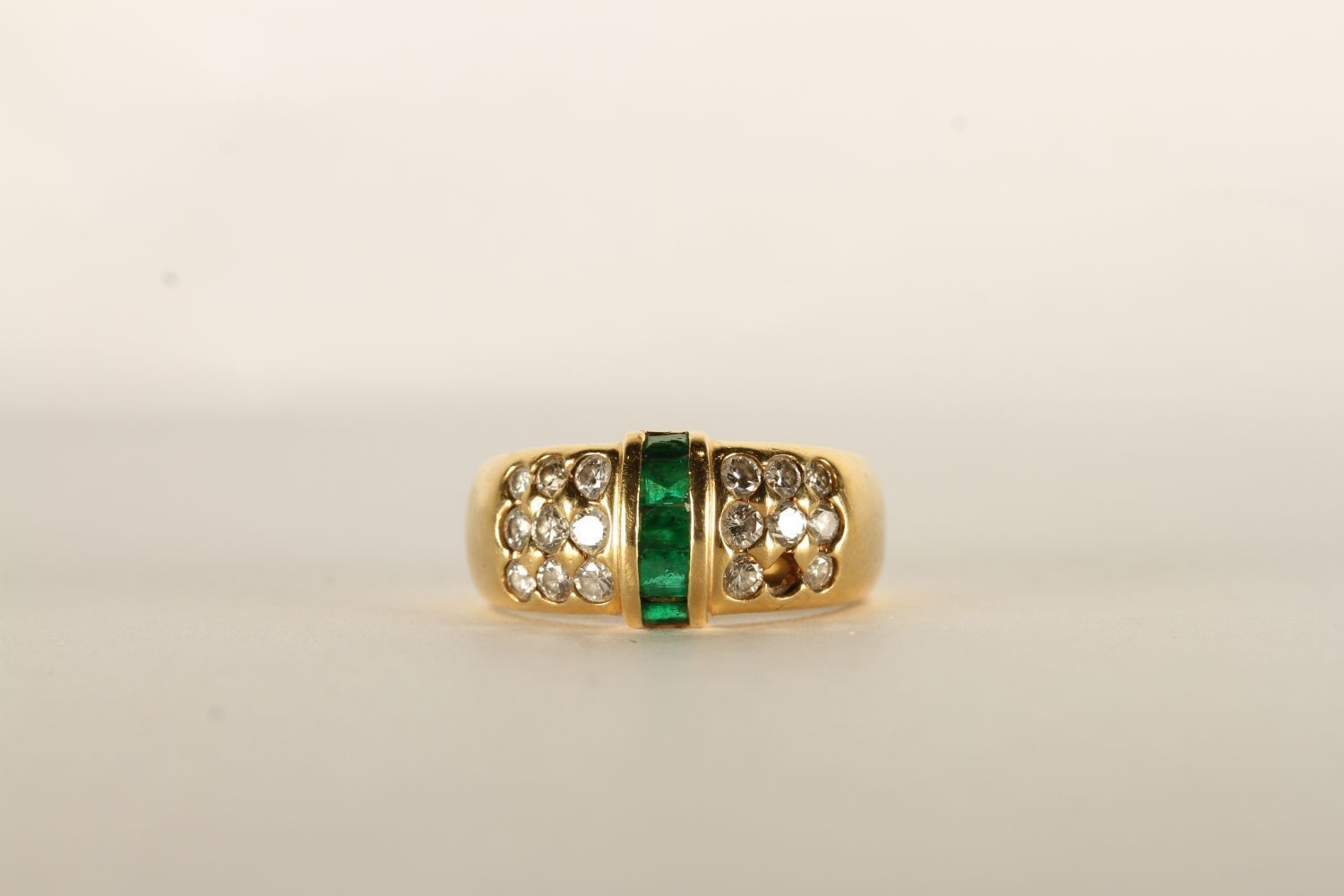 Emerald and Diamond Ring, set with baguette cut emeralds to the centre, surrounded by round