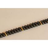 HAEMATITE TWO ROW BRACELET WITH YELLOW METAL DIAMOND SET BARS AND CLASP, black stones estimated as