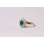Oval Cut Emerald and Diamond Cluster Ring, set with an emerald totalling approximately 0.80ct and