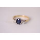 18ct Sapphire and Diamond three stone ring, central oval cut blue sapphire, a brilliant cut