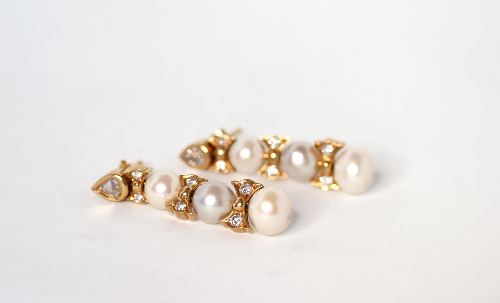 Pearl and diamond drop earrings, three graduating pearls with diamond set bow spacers, flat cut - Image 2 of 2