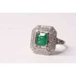 Platinum ring set with a large emerald-cut emerald, the emerald is surrounded by two octagonal halos