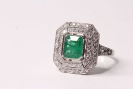 Platinum ring set with a large emerald-cut emerald, the emerald is surrounded by two octagonal halos