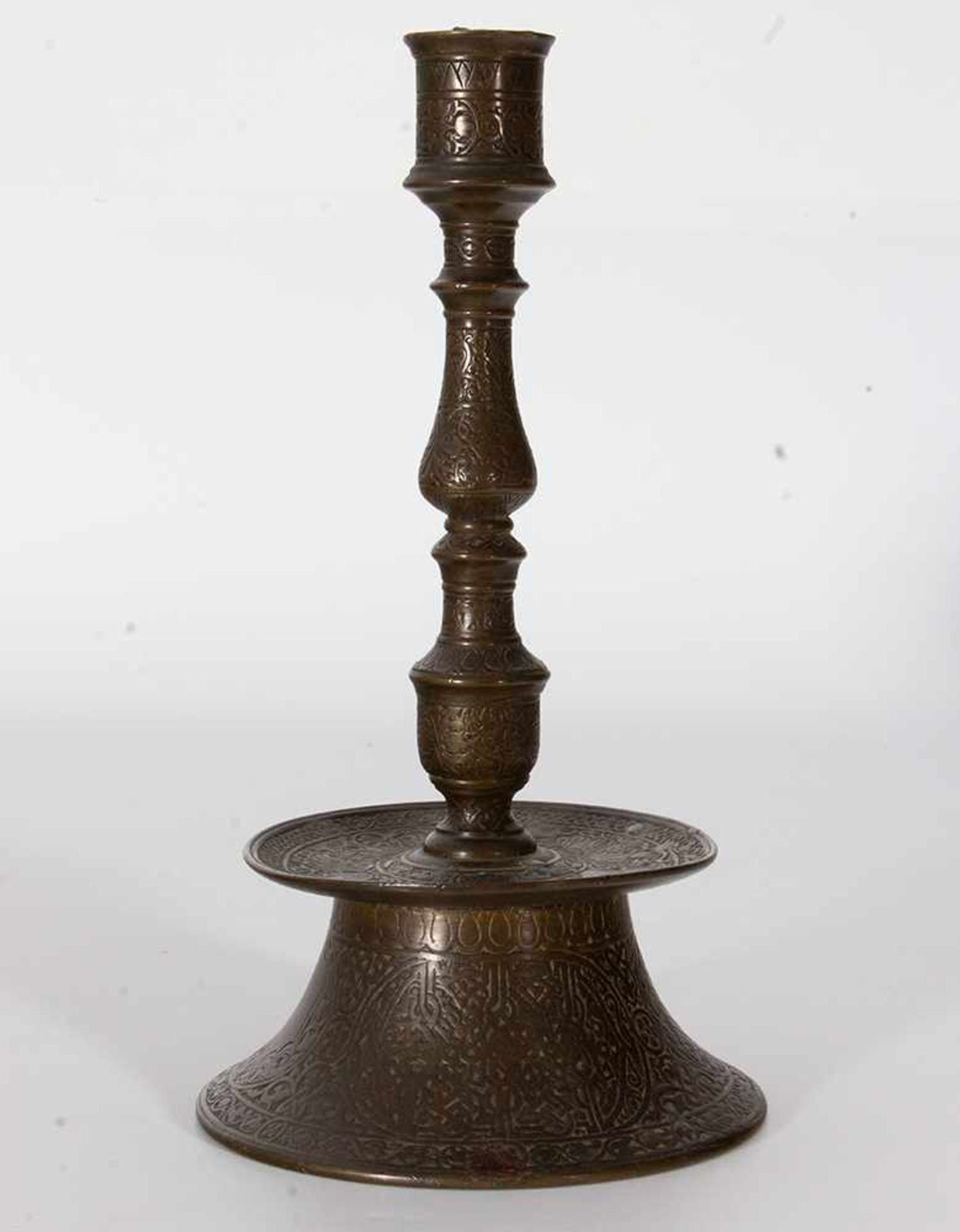 Dos candeleros islámicos en bronce con decoración estilizada, uno con incrustaciones en plata, de