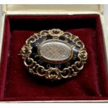 Large victorian gold and enamel mourning brooch with central glass panel set with plaited hair engra