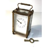 Brass carriage clock and key winds and ticks but no warranty is given front glass panel corner