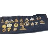 Collection of military cap badges attached to old cloth