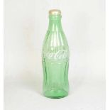 Huge glass Coca-Cola bottleHuge Coca-Cola bottle made out of light green glass with a plastic cap.