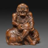 STATUETTE - en bambou sculpté, représentant un luohan assis sur un lion, la bouche [...]