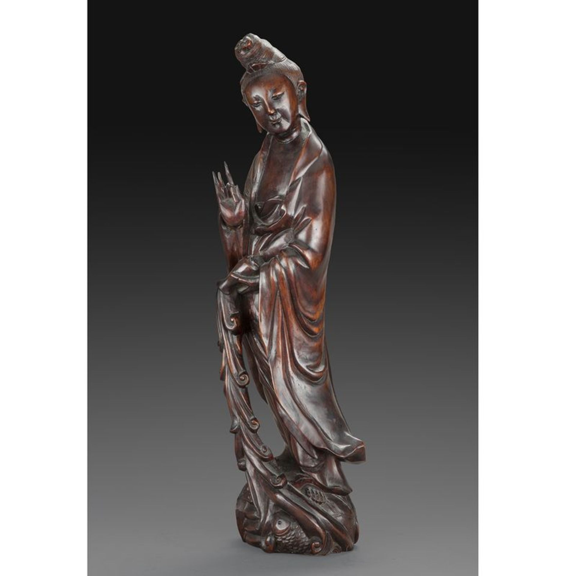 STATUETTE DE GUANYIN - en bois naturel, représentée en pied sur un rocher, [...]