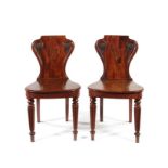 A pair of George IV carved mahogany hall chairs