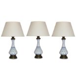 A set of three white and blue ceramic table lamps