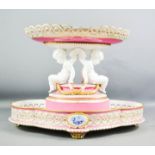 A large Minton tazza centrepiece, with pink ground, modelled with cherubs, blue and white oval to