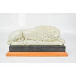 A model recumbent lion, blue and white flecked resin, raised on a marble and wooden plinth, 22cm