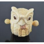 A novelty tape measure in the form of an owl, circa 1900, carved bone with glass eyes, 5½cm high.