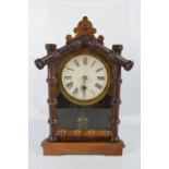A mantle clock with Roman numeral dial, and bamboo style frame.