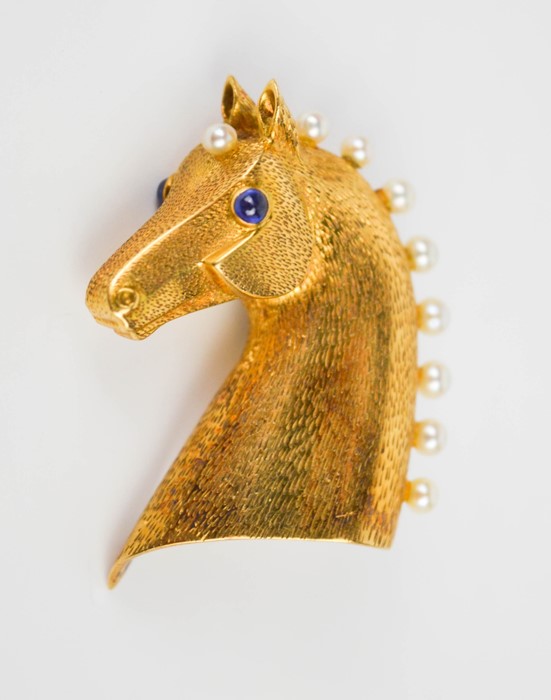 An 18ct gold Cartier brooch in the form of a horses head, finely engraved with detail, inset with