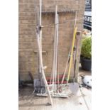 A quantity of long handled garden tools including rakes, scythes, turf spade and other items.