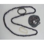 A group of pearl necklaces: two grey pearl examples and bracelet, and a white pearl bracelet.