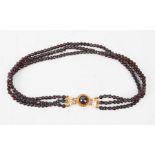 A garnet and yellow metal choker necklace, with three beaded strands.