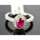 An 18ct white gold, ruby and diamond ring, 1ct ruby, surrounded by diamonds and to the shoulders