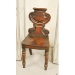 A 19th century mahogany hall chair with scroll carved crested back, and turned front legs.