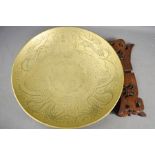 A Chinese brass bowl engraved with decoration, raised on hardwood carved x-form stand.