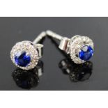 A 9ct pair of white gold, sapphire and diamond 'halo' stud earrings, 1.2g.