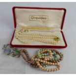 A group of pearl necklaces, including one with multi coloured strands.